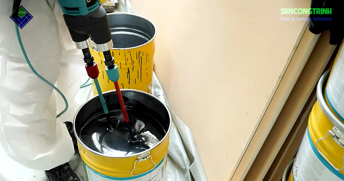 Kỹ thuật viên sử dụng máy khuấy để trộn vật liệu sơn sàn epoxy hai thành phần trước khi thi công