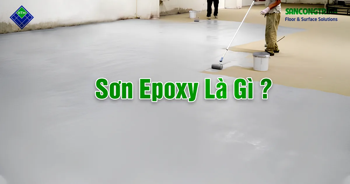 Thợ thi công lăn sơn epoxy trên sàn nhà xưởng — bề mặt chuyển từ nền bê tông thô sang lớp phủ epoxy hoàn thiện màu xám